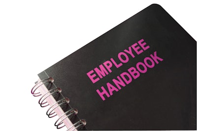 Employee handbook on a wooden table and glasses.
