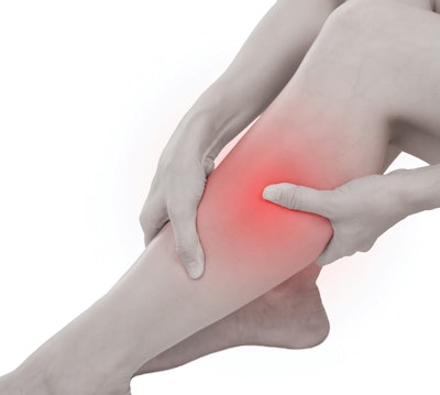 Woman with calf feeling pain on white background.