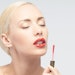 PhoenixWomanApplyingRedLipGloss850x425