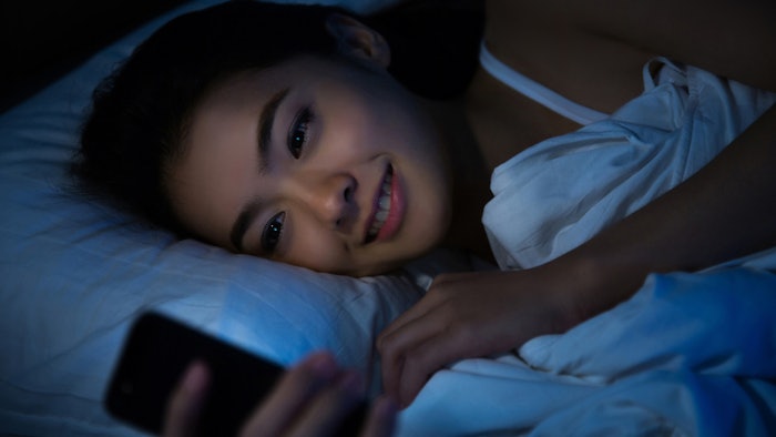 woman smiling at her phone before bed
