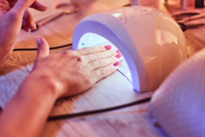 Client cures gel nails in UV light