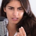 Woman looks at hair falling out of scalp while holding a brush in hand.