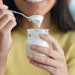 An individual snacks on a yogurt.