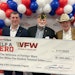 Veterans hold $1.5 million check from Sport Clips Haircuts.
