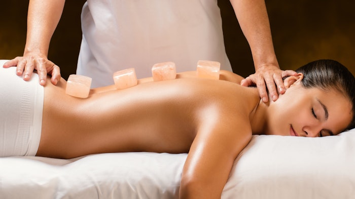 Woman having hot himalayan stone massage in spa.