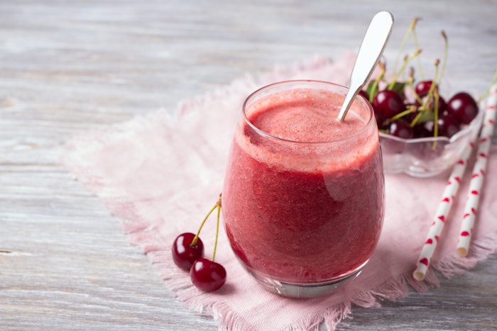 Cherry smoothies with fresh cherries on a wooden table