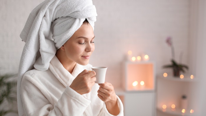 Beautiful young woman with cup of tea relaxing in spa salon By Pixel-Shot