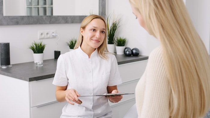 Consultation in cosmetology clinic. Female professional beauty doctor talking with pretty young female.