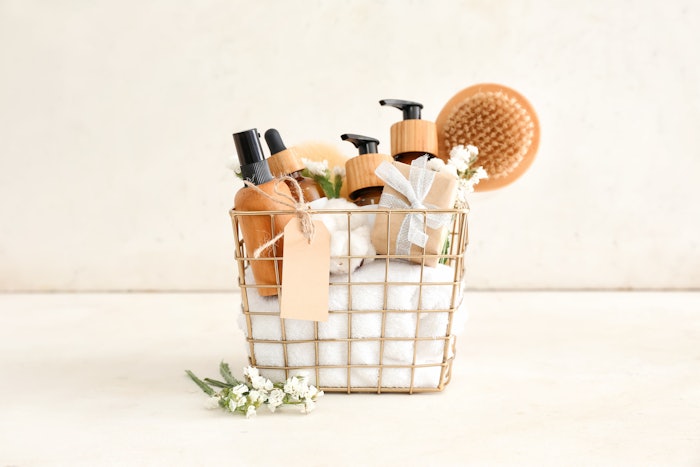 Gift basket with cosmetic products on light background