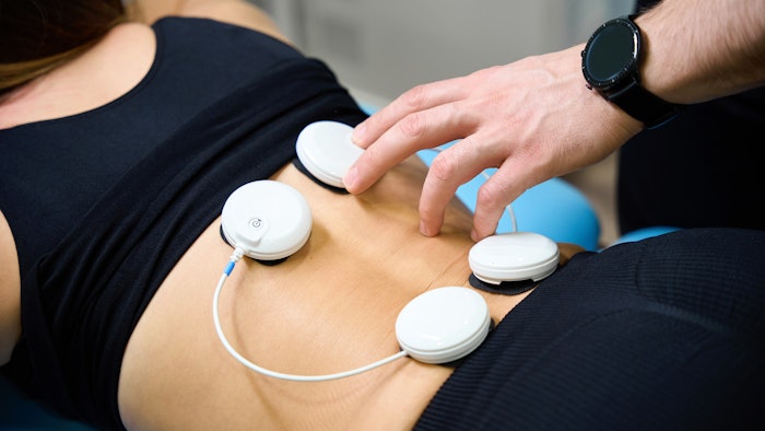 Doctor uses muscle electrical stimulator for wellness procedure in rehabilitation center