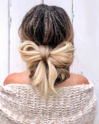 Hair braided into a bow and styled with gold glitter