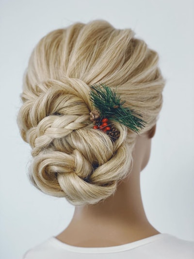 A holiday updo by @annette_updo_artist styled with pine and a pinecone.