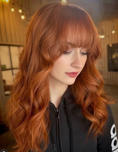 A person with wavy, copper hair and bangs.