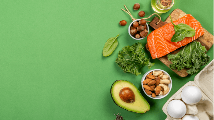 Keto diet concept - salmon, avocado, eggs, nuts and seeds, bright green background, top view