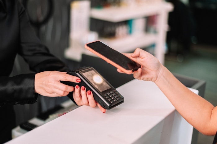 Person paying for beauty services using their smartphone.