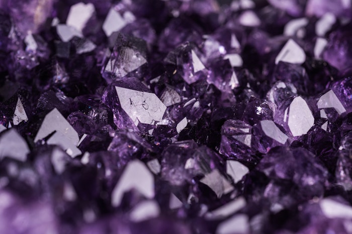 Amethyst geode on black background. Beautiful natural crystals gemstone. Extreme close up macro shot.