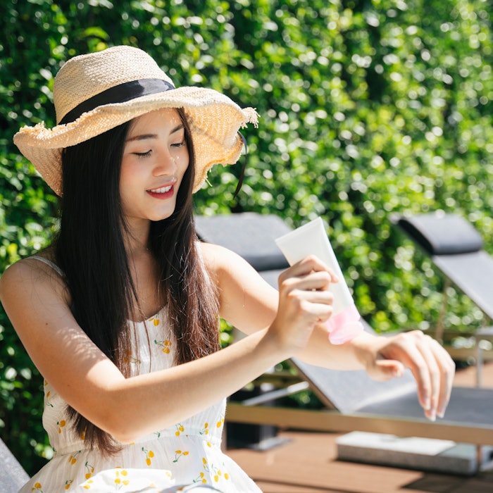 YoungAsianWomanOutsideApplyingSunscreen