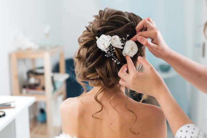 Stylist putting floral accessories in her bridal client's hair.