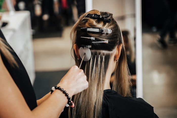 Hairstylist applying hair extensions to a client.