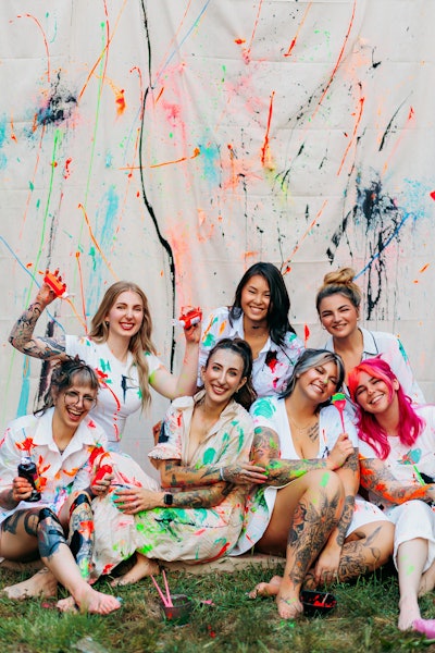 Lauren Peters and her salon staff wearing paint splattered clothes and posing in front of a paint splattered background.