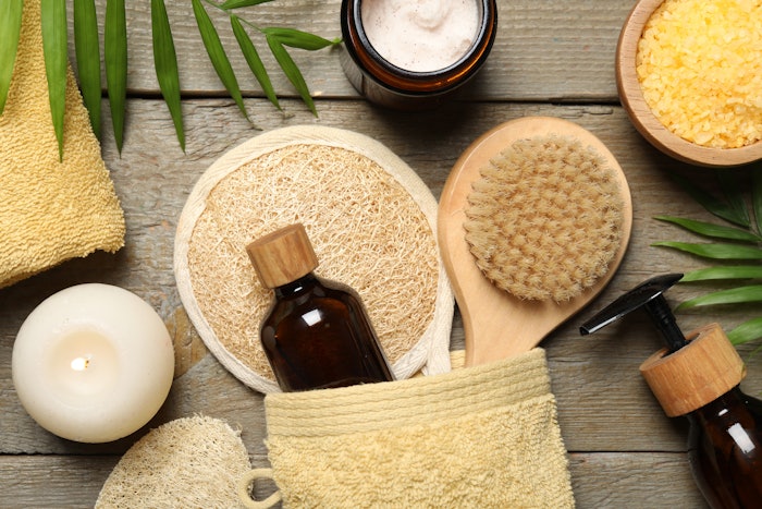 Spa composition with different cosmetic products and burning candle on wooden table, flat lay