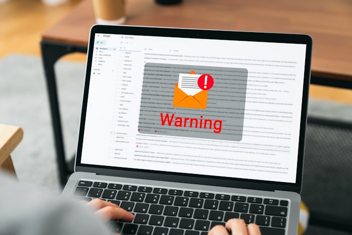Hand using laptop with shows a warning screen of new email notifications