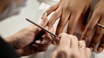 Nail tech files a client's nails in the salon.