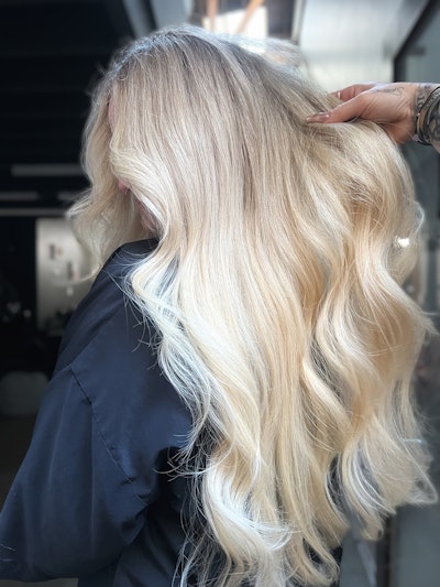 A model with bright, blonde hair, cascading in waves down her head.