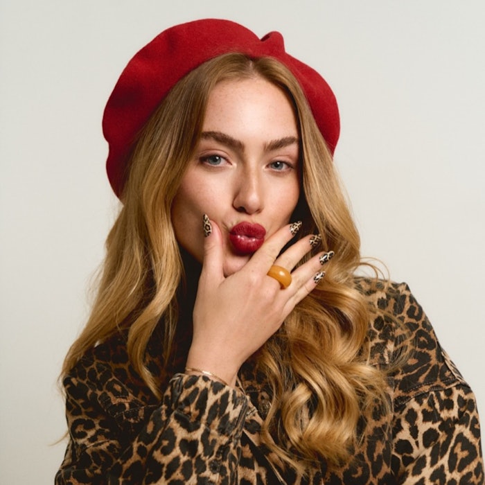 Model in a red beret and leopard print jacket wearing Twisties' leopard print design.
