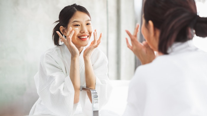 Beautiful Asian Woman Applying Face Cream Bathroom Sink Setting
