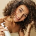 Woman With Beautiful Curly Hair Holding Product Feeling Curls
