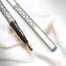 Two metallic precision drill bits with intricate geometric pattern handles