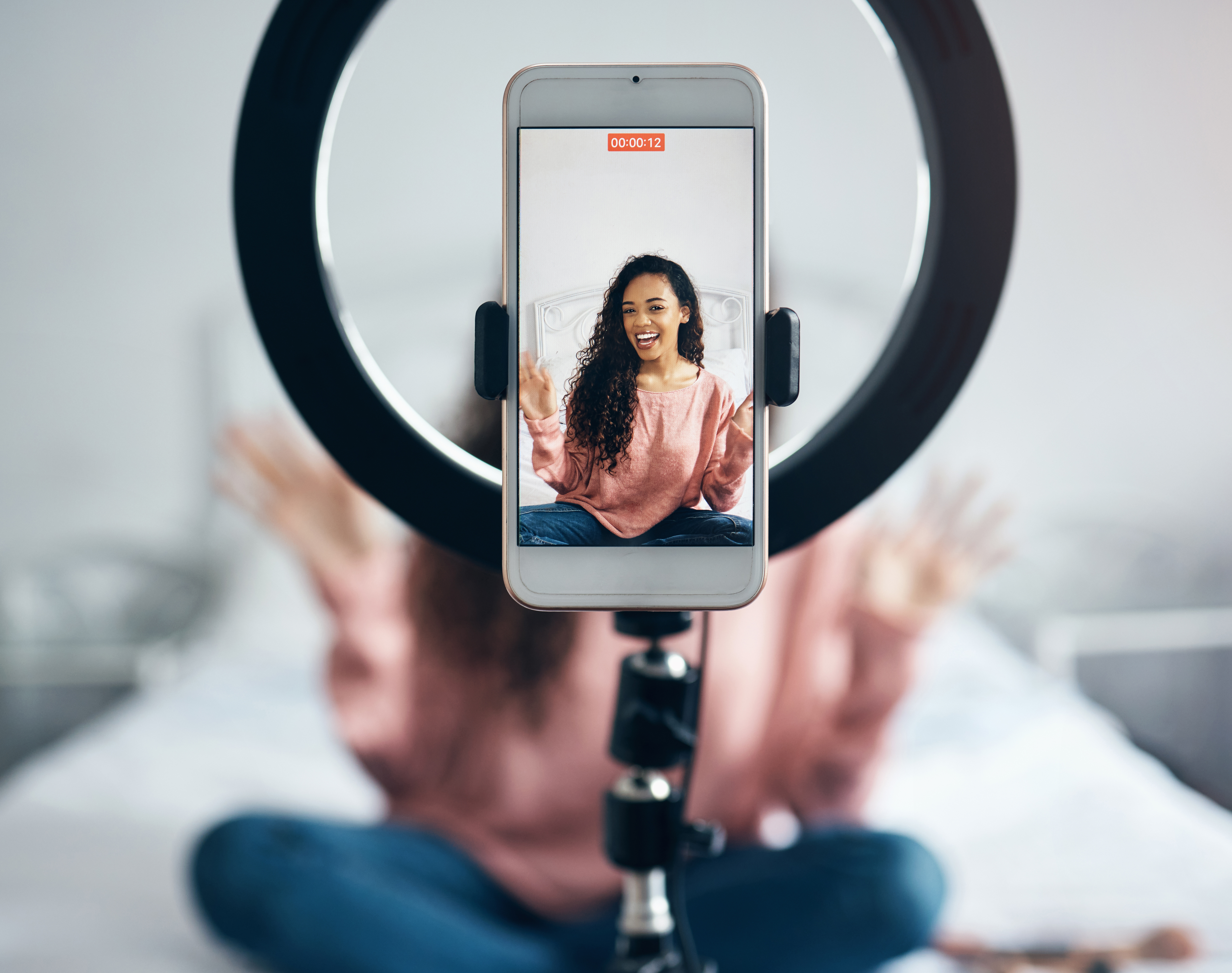 Woman smiling during video call on smartphone mounted on ring light for content creation