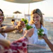 Friends toasting with drinks at a beach sunset celebration