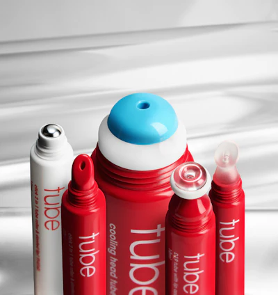Collection of red and white cosmetic tubes with blue-capped skincare product displayed on white surface with dramatic lighting
