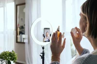 Woman applying skincare serum while recording video with ring light and smartphone for content creation