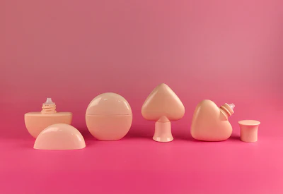 Collection of peach-colored decorative cosmetic containers and vessels arranged on a pink background