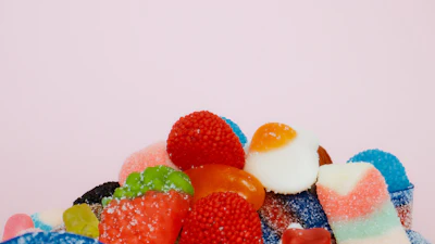 Assorted colorful gummy candies with sugar coating on pastel purple background
