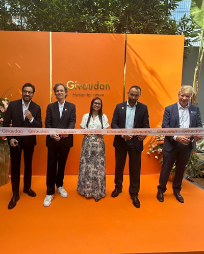 Five business professionals at Givaudan ribbon-cutting ceremony with orange branded backdrop