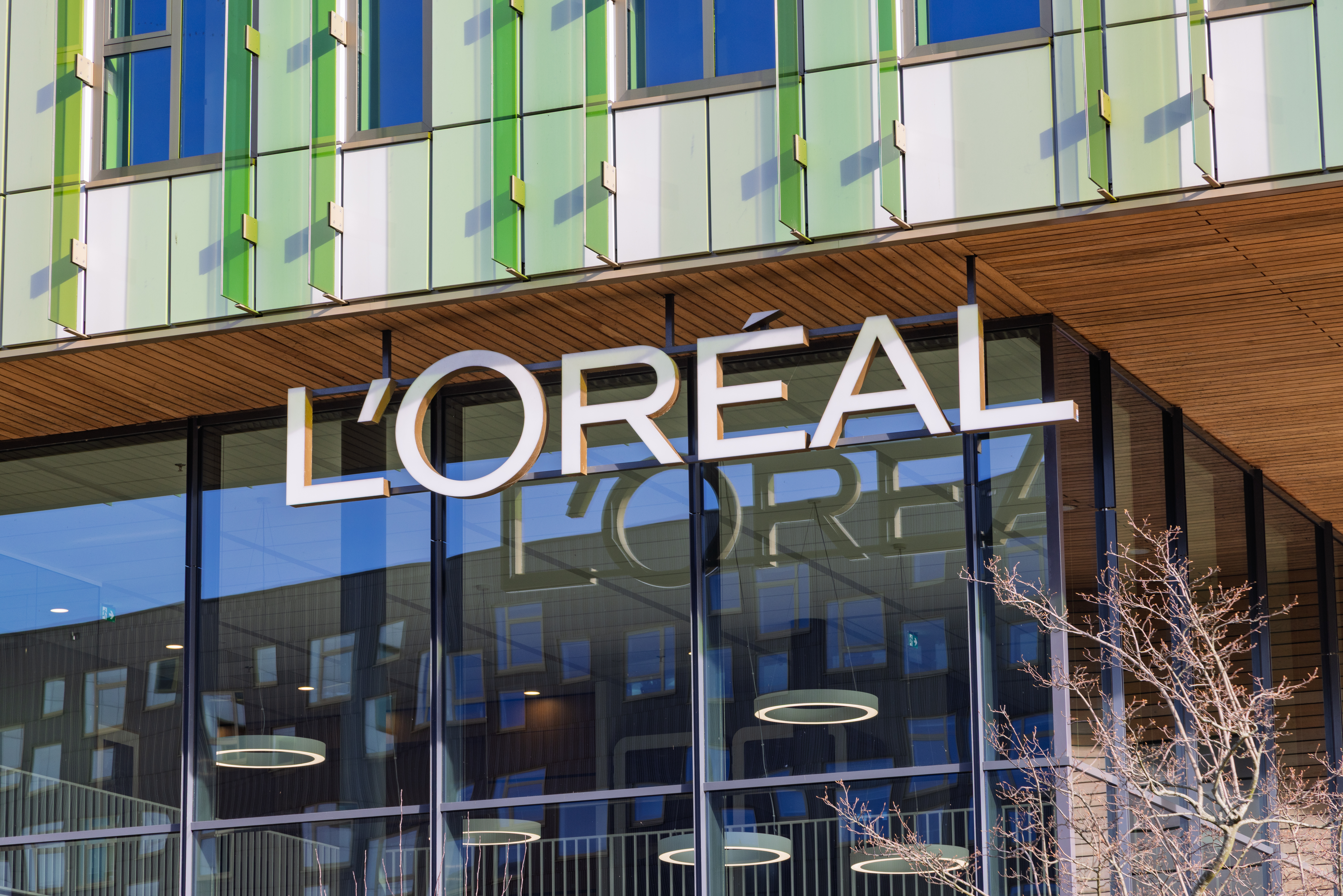 L'Oréal storefront with white signage on modern building with green-framed windows and wooden architectural elements