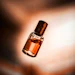 Golden amber fragrance bottle with dark cap against warm, blurred background
