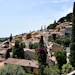 Hillside Mediterranean village with terracotta buildings, cypress trees, and colorful facades overlooking coastal landscape