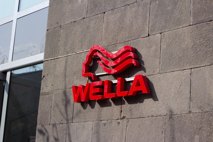 Wella red neon logo sign mounted on concrete building wall