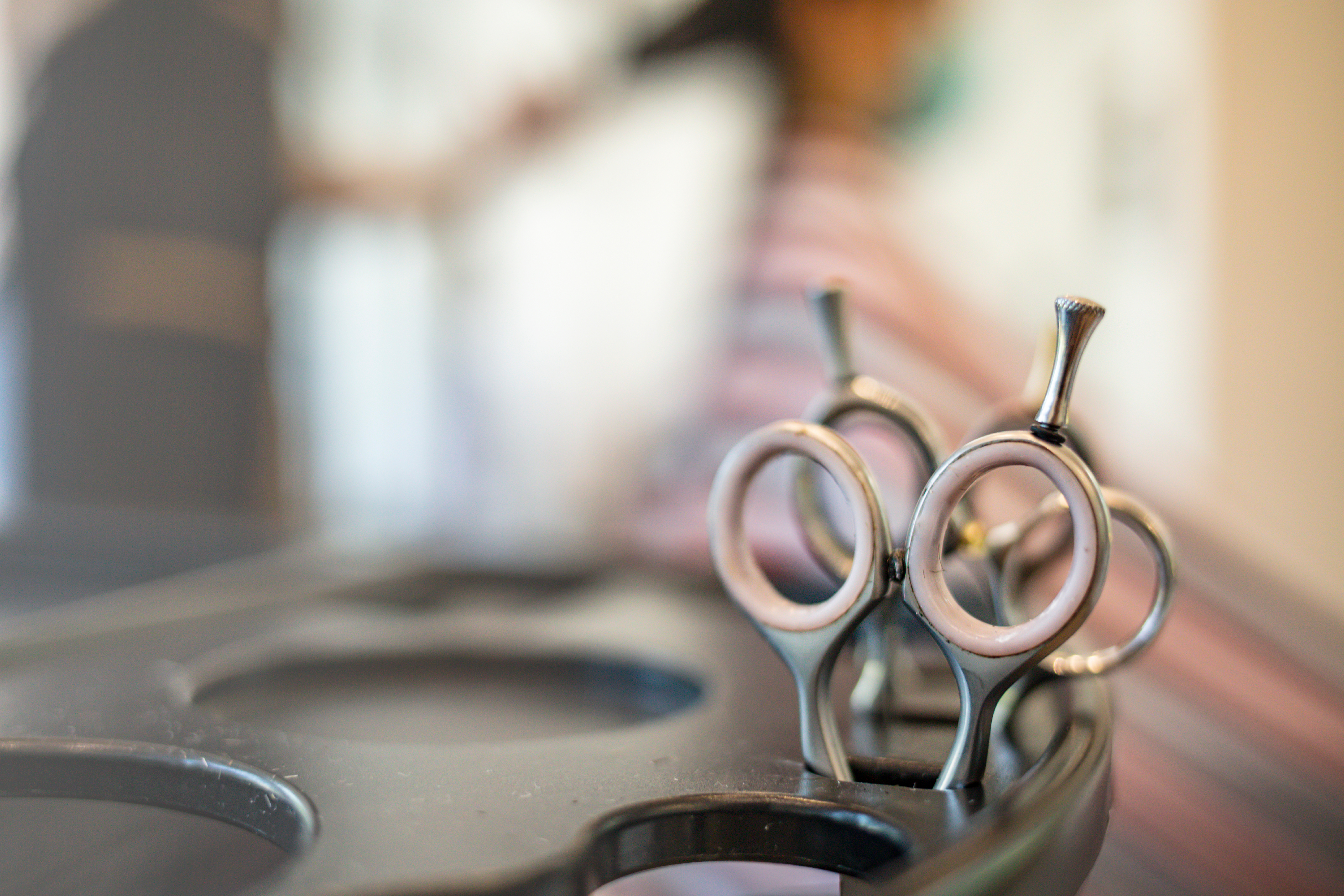 Professional hairdressing scissors displayed on salon counter with blurred salon background