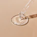 Clear liquid serum dispensed from dropper into glass dish on beige background