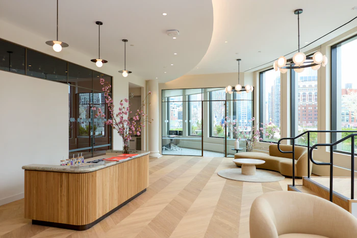 Modern luxury apartment lobby with wooden reception desk, contemporary seating, floor-to-ceiling windows overlooking city skyline