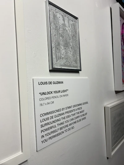 Gallery wall displaying framed intricate illustration by Louis de Guzman titled 'Unlock Your Light' with exhibition label