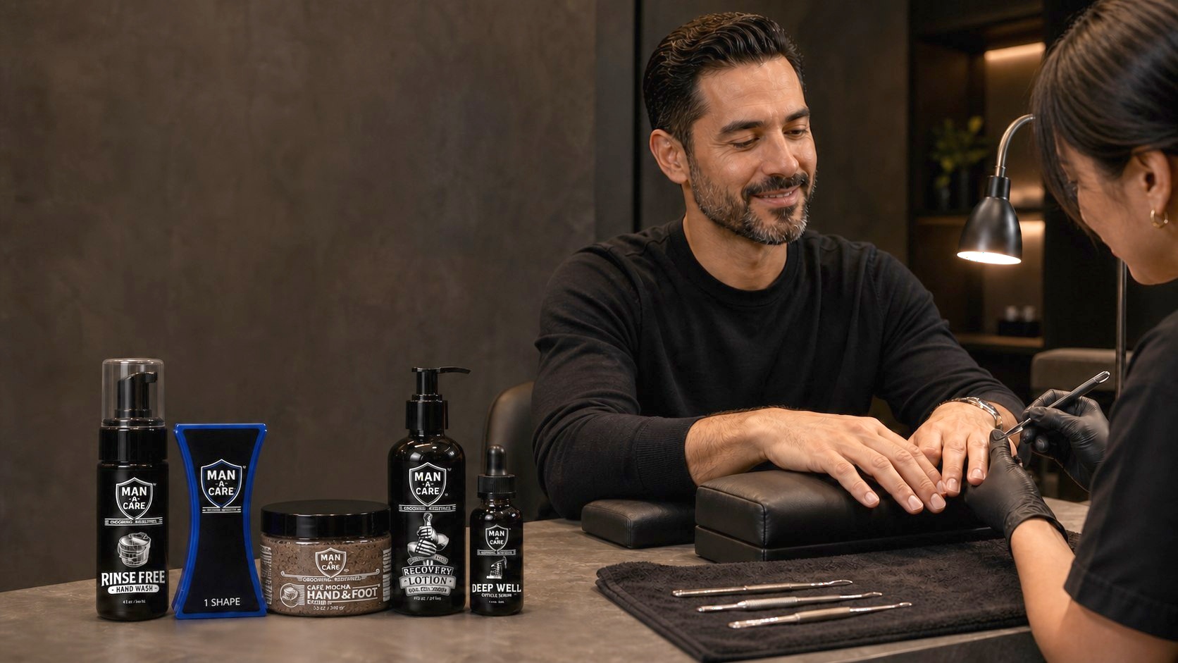 Male groomer consulting with client at counter displaying ManCave men's grooming products