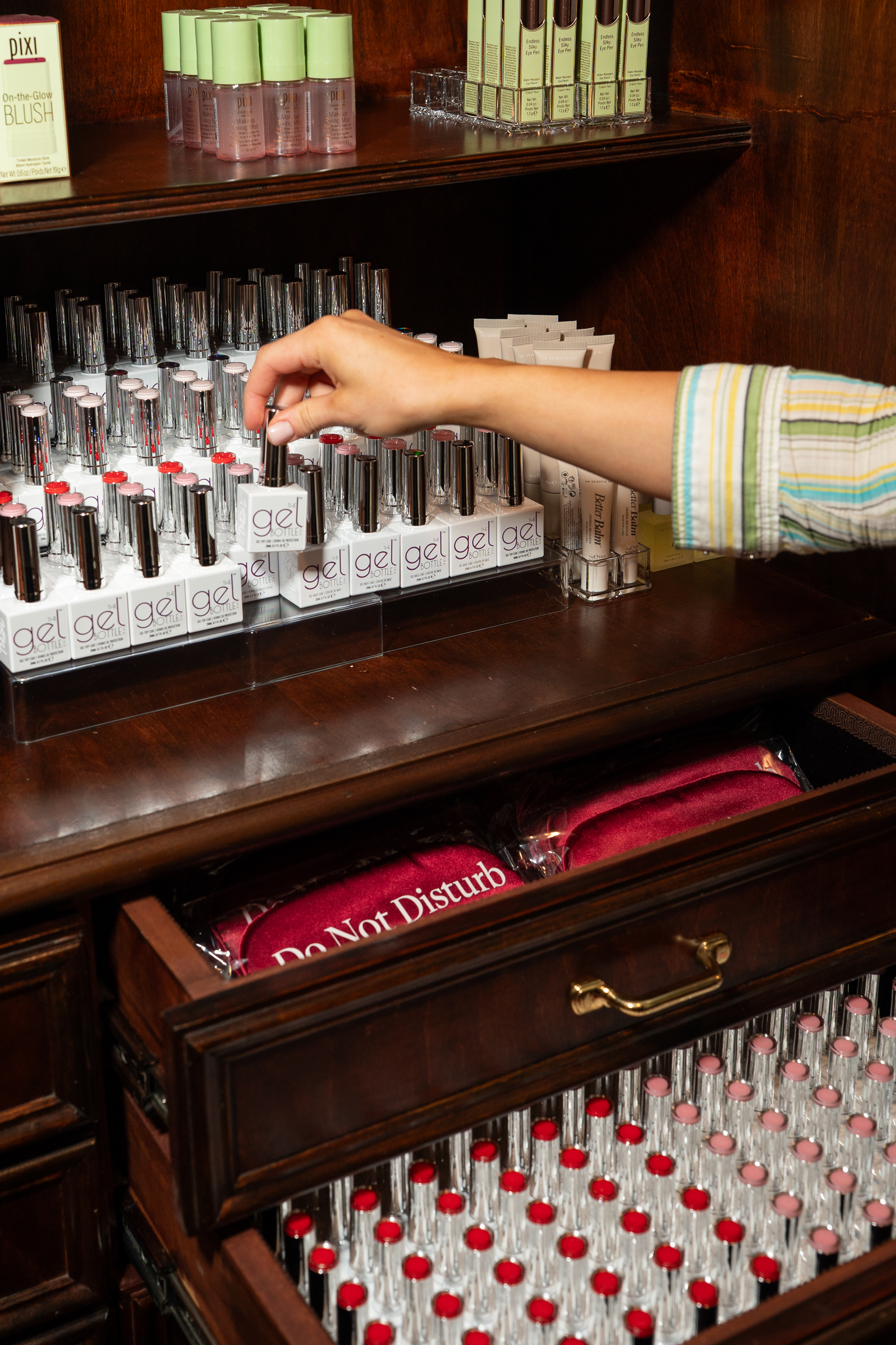 Beauty counter display with gel nail polish bottles and cosmetic products organized on wooden shelves