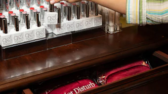 Beauty counter display with gel nail polish bottles and cosmetic products organized on wooden shelves